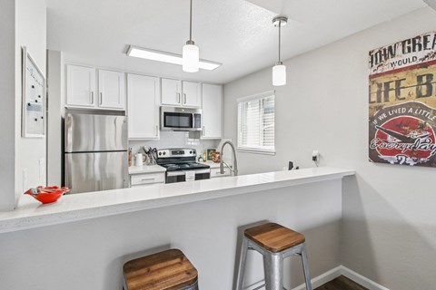 A kitchen with white cabinets and a fridge.