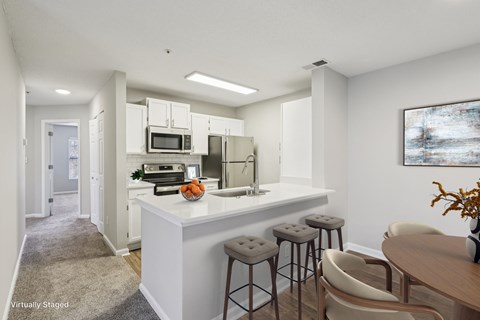 A kitchen with a white counter and bar stools.