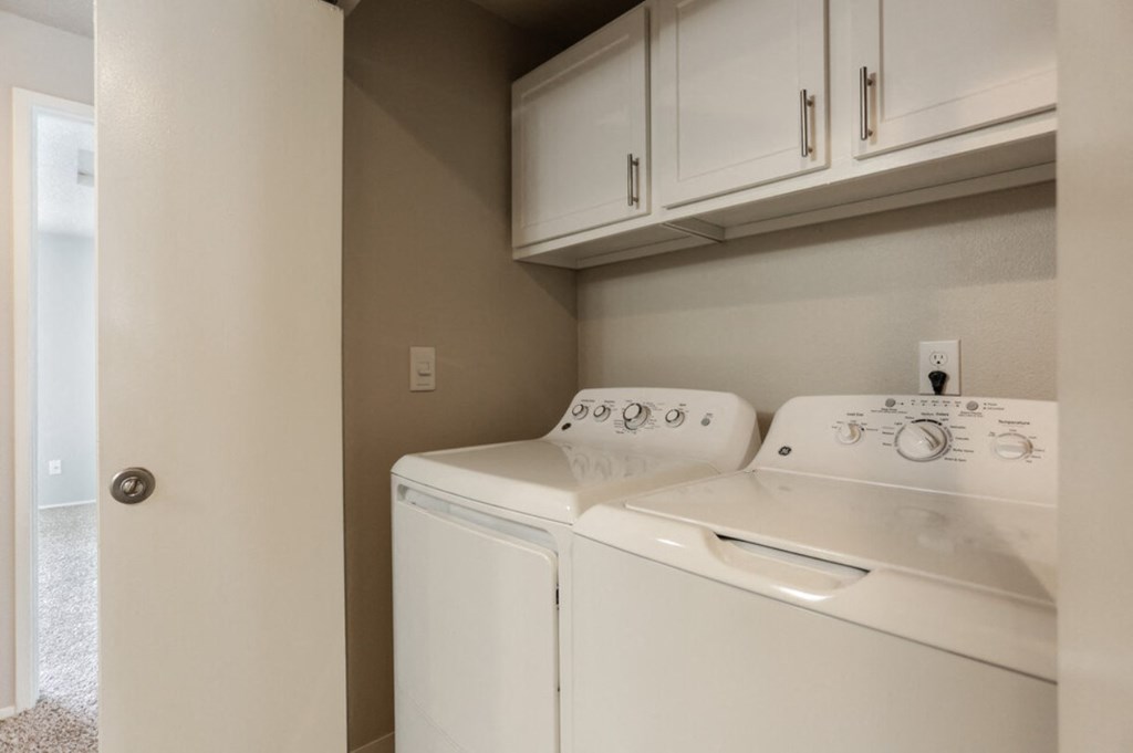 a white washer and dryer in a kitchen with white cabinets and a door