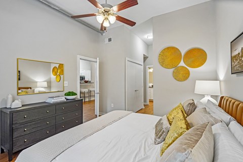 A bedroom with a white bed and a ceiling fan.