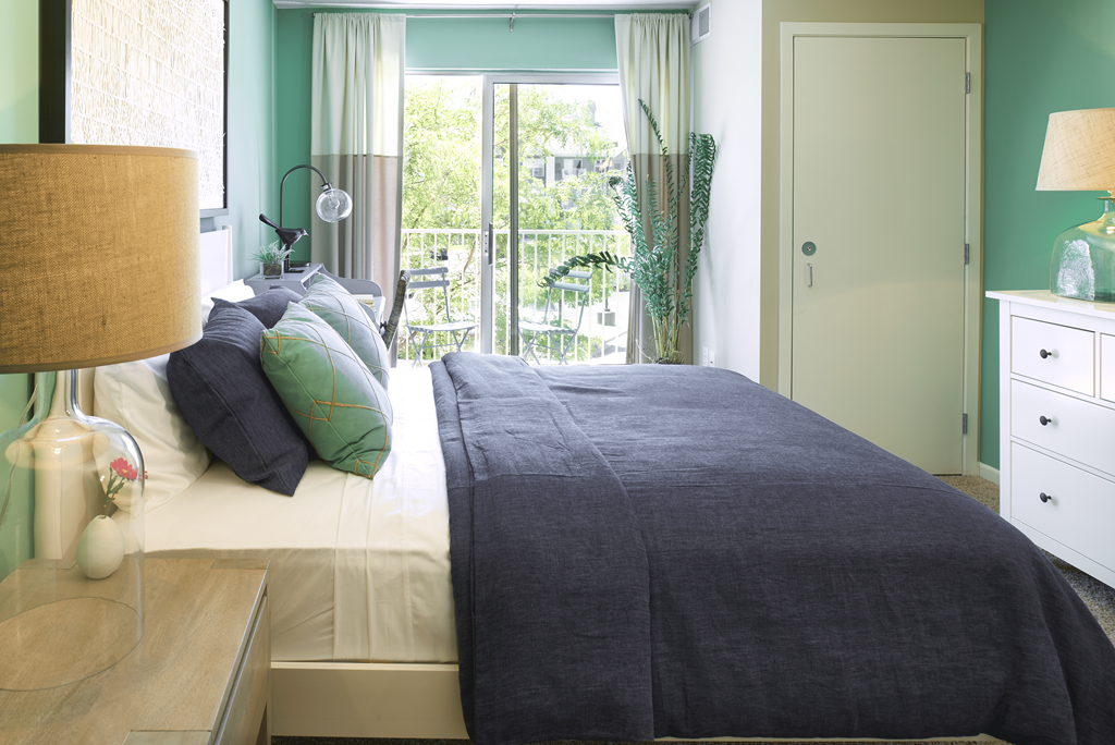a bedroom with green walls and a bed with a gray blanket