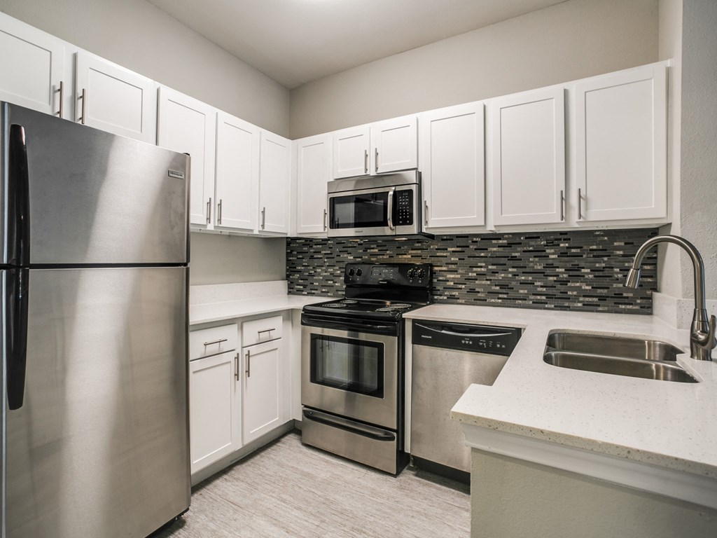 Townhomes in Houston, TX - The Maroneal - Modern Kitchen with White Countertops, Stainless Steel Appliances, Hardwood Flooring, and White Cabinetry