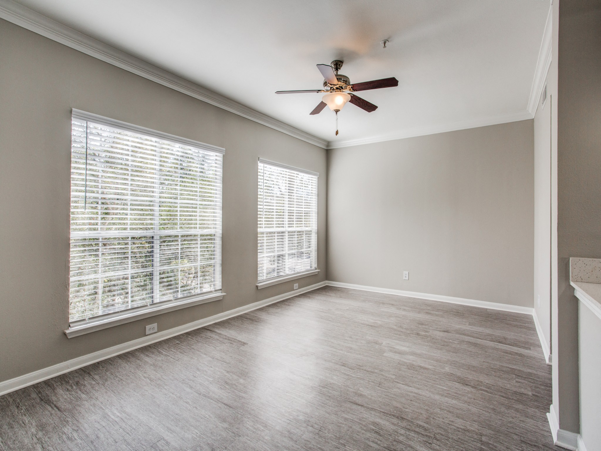 Apartments for Rent Houston - Open-Concept Living Room with Wood Flooring, Two Large Windows, and a Ceiling Fan