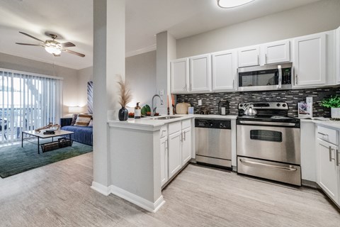 spacious kitchen with stainless steel appliances and white cabinets in an apartment