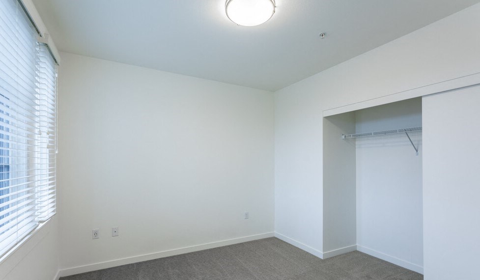a bedroom with white walls and a large window