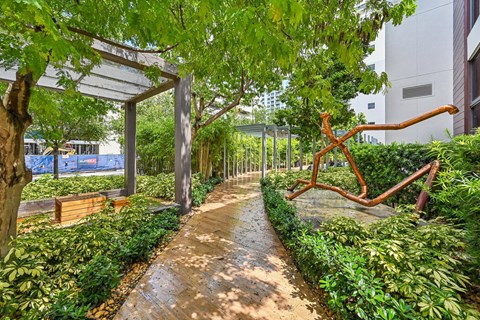 A walkway in a park with a bench and a sculpture.