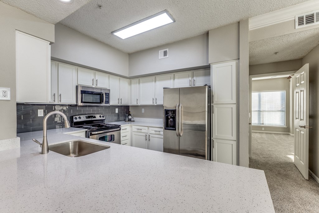 an open kitchen with stainless steel appliances and white counter tops