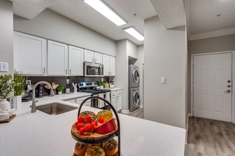 a kitchen with white cabinets and a counter top with a fruit basket