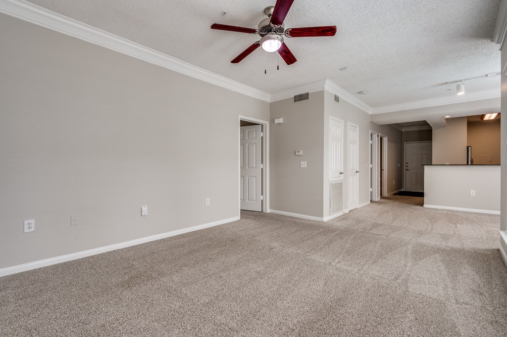 an empty living room with a ceiling fan