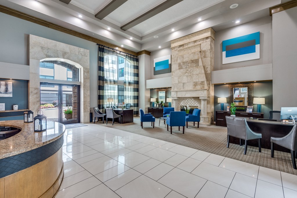 the lobby of a hotel with tables and chairs and a fireplace