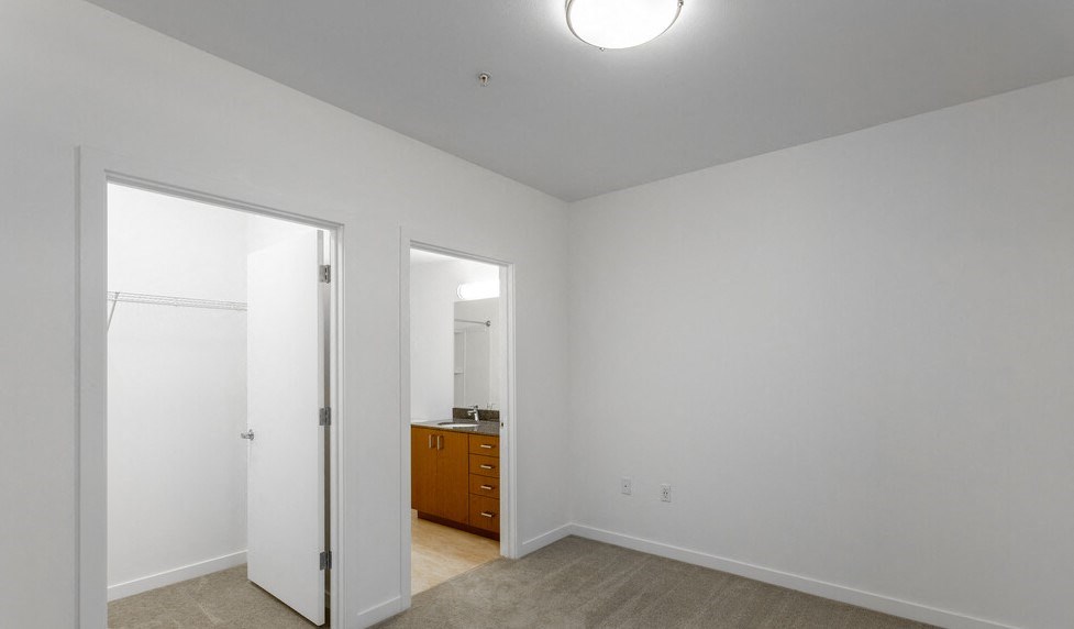 a bedroom with white walls and a door to a bathroom