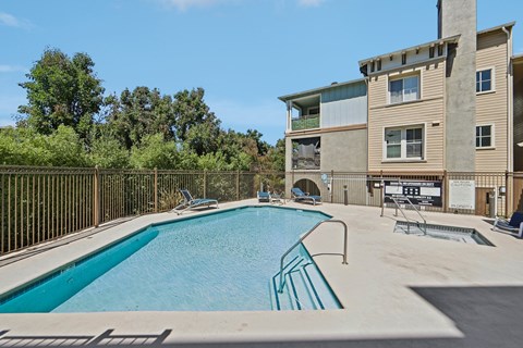 A swimming pool in front of a building with a fence around it.