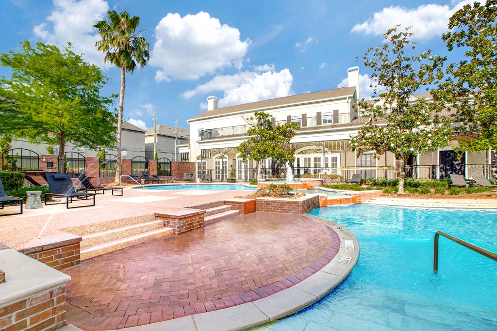 A swimming pool surrounded by a brick patio and a building in the background.