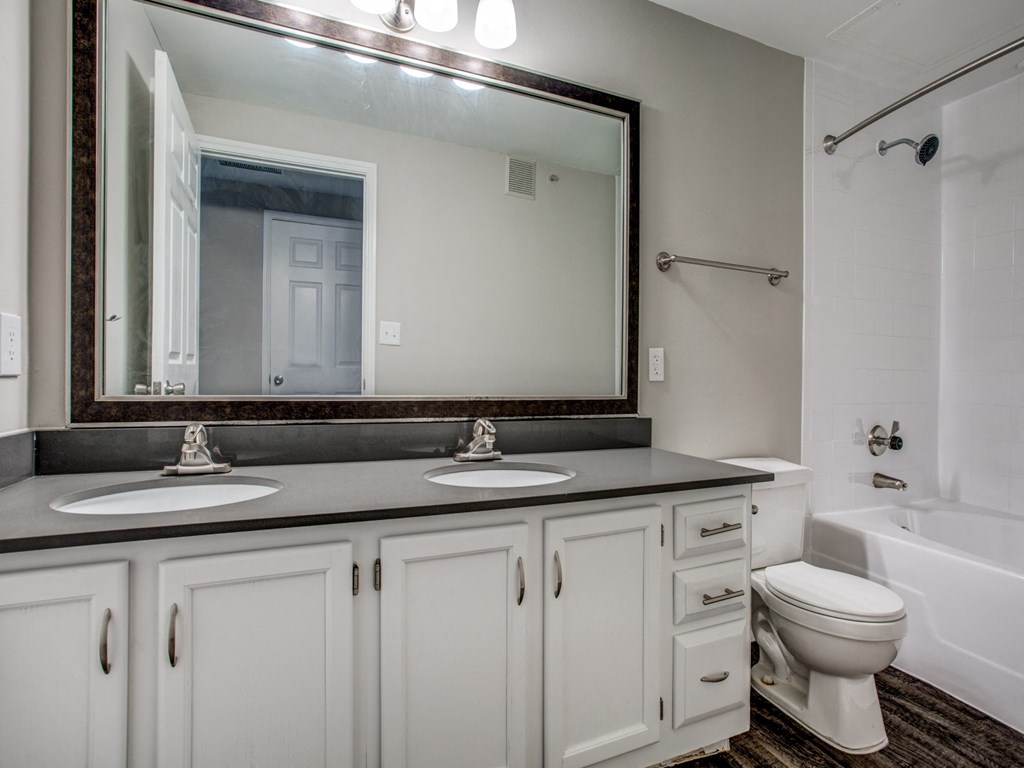 a bathroom with white cabinets and a mirror and a toilet and a sink