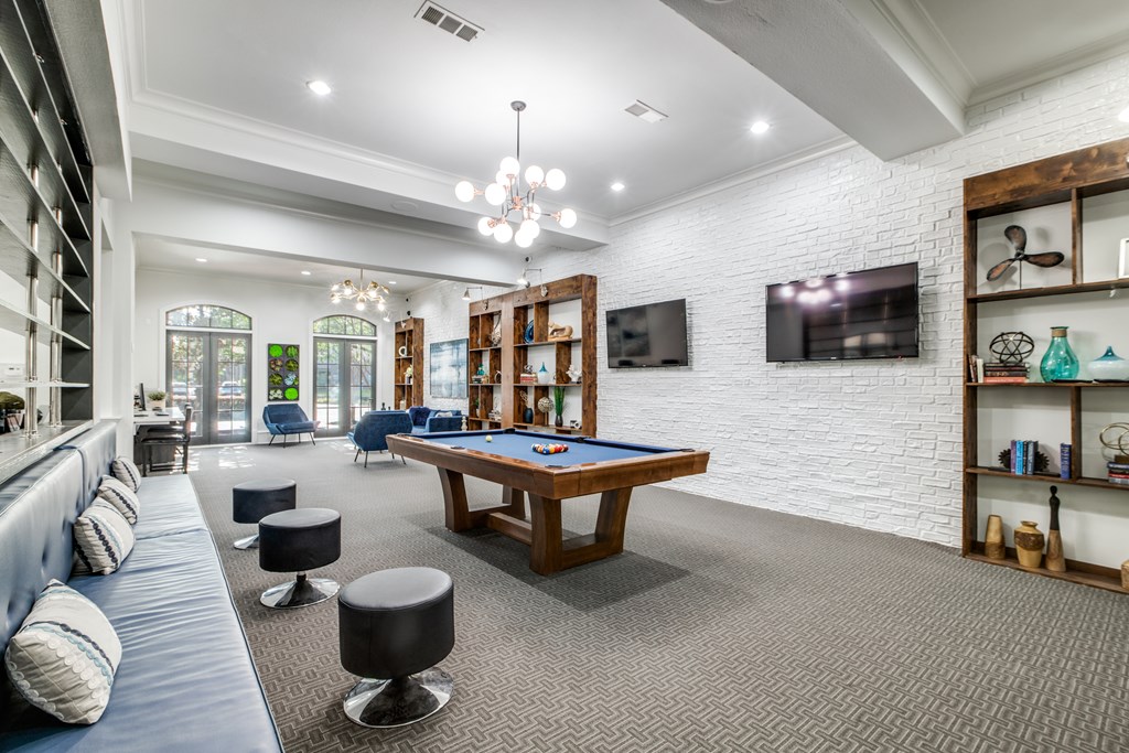 A room with a pool table and a television mounted on the wall.