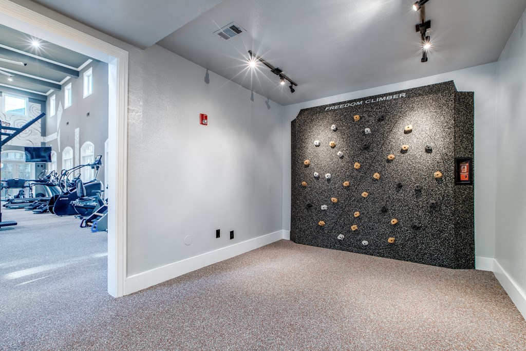A room with a climbing wall and a gym in the background.