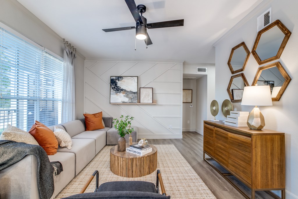 A living room with a grey couch, a wooden coffee table, and a ceiling fan.