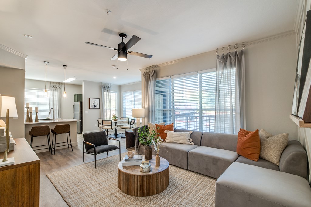 A living room with a grey couch, a wooden coffee table, and a ceiling fan.