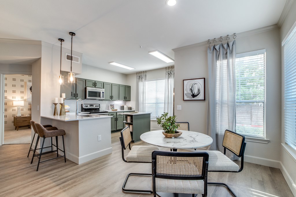 A kitchen with a table and chairs in front of a window.