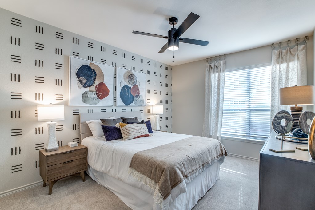 A bedroom with a bed, nightstand, and a ceiling fan.