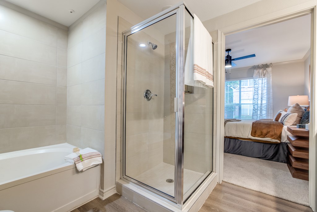 A bathroom with a glass shower door and a white bathtub.