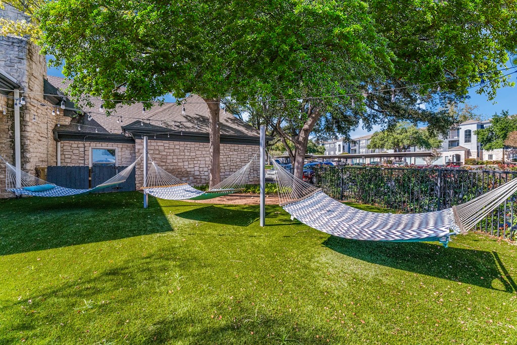 two hammocks on the grass in front of a house