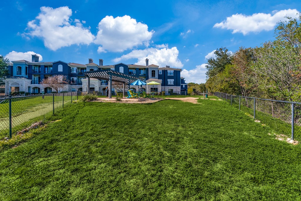 a yard with a fence and houses in the background