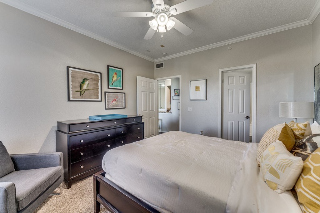 the master bedroom has a king size bed and a dresser and chair