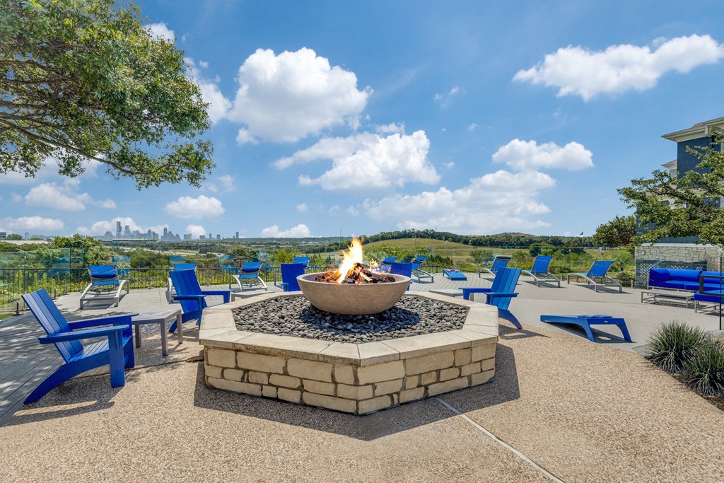 a fire pit with blue chairs and a view of the city