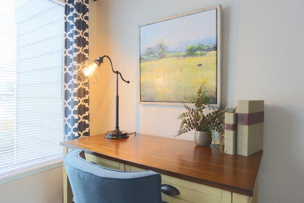 a desk with a chair and a painting on the wall