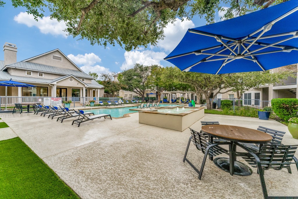 Two-Bedroom Apartments in Austin, TX - Parkside Crossing - Resort-Style Pool with Spacious Sundeck, Lounge Seats, Spa, and Umbrellas with Tables and Chairs.