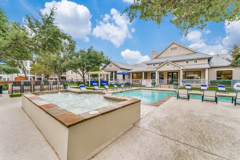 Two-Bedroom Apartments in Austin, TX - Parkside Crossing - Swimming Pool with Raised Bubbly Hot Tub, Lounge Chairs, Pergola, High-Top Table, Bar Stools, Metal Fence, and Trees.