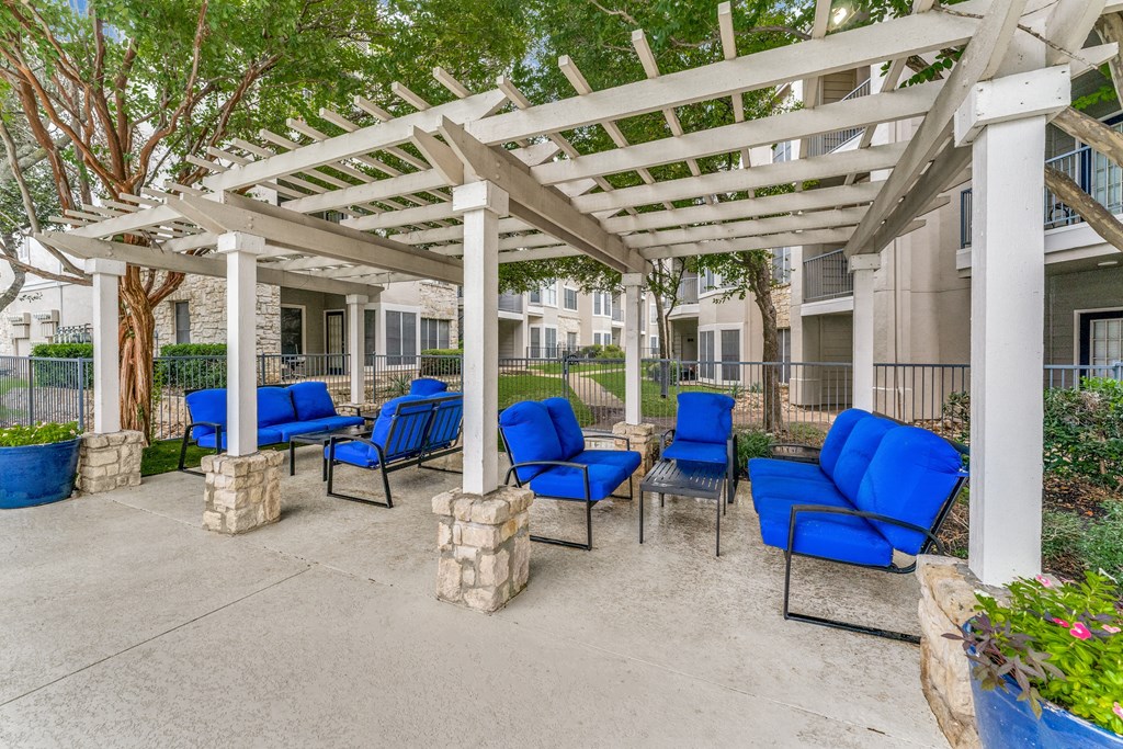 a covered patio with blue chairs and a white pergola