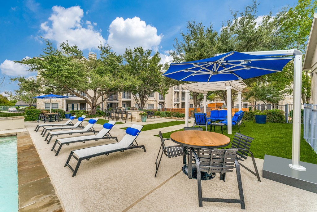 a patio with chairs tables and umbrellas and a pool