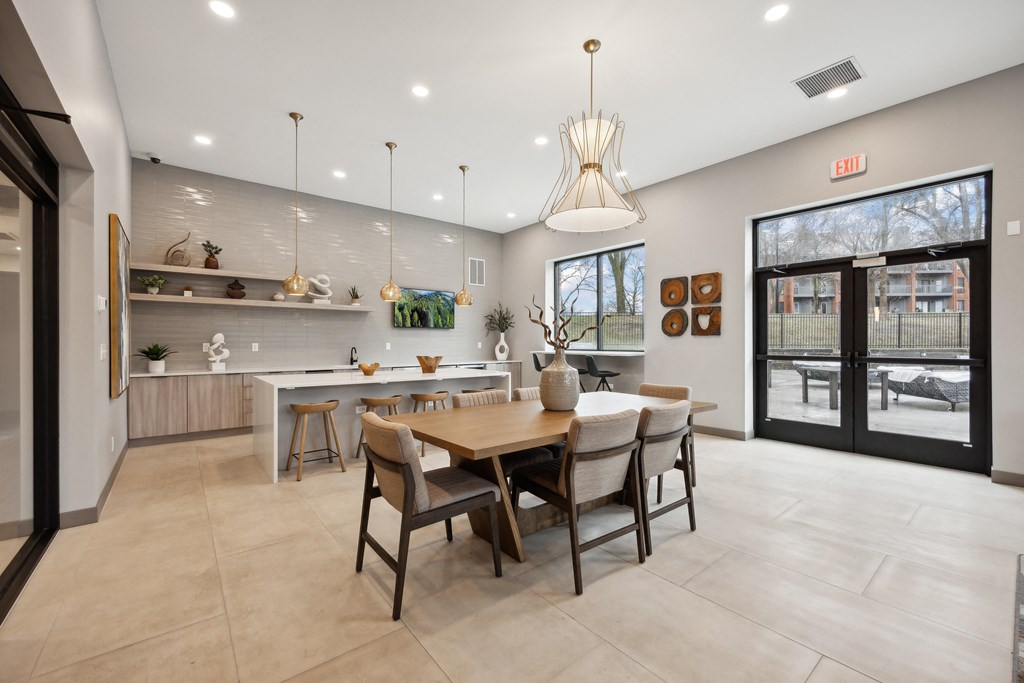the gathering room and kitchen of a home with a dining table and chairs