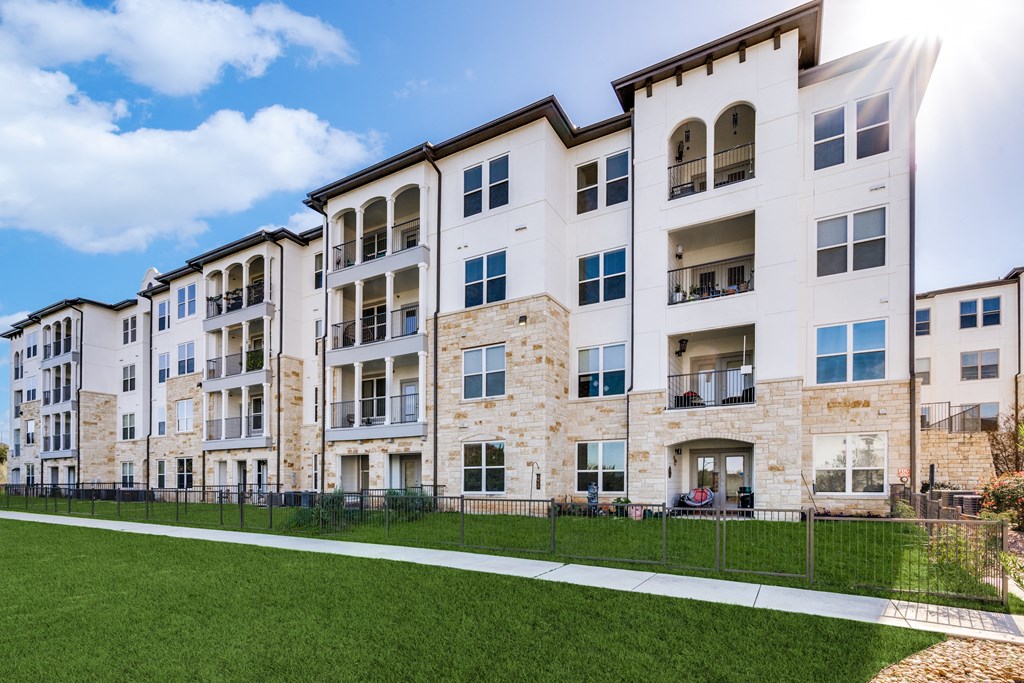 an image of an apartment building with green grass and a sidewalk
