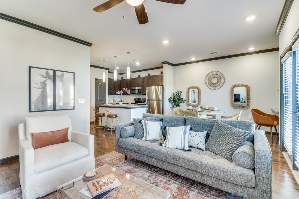 a living room with a couch and a chair in front of a kitchen