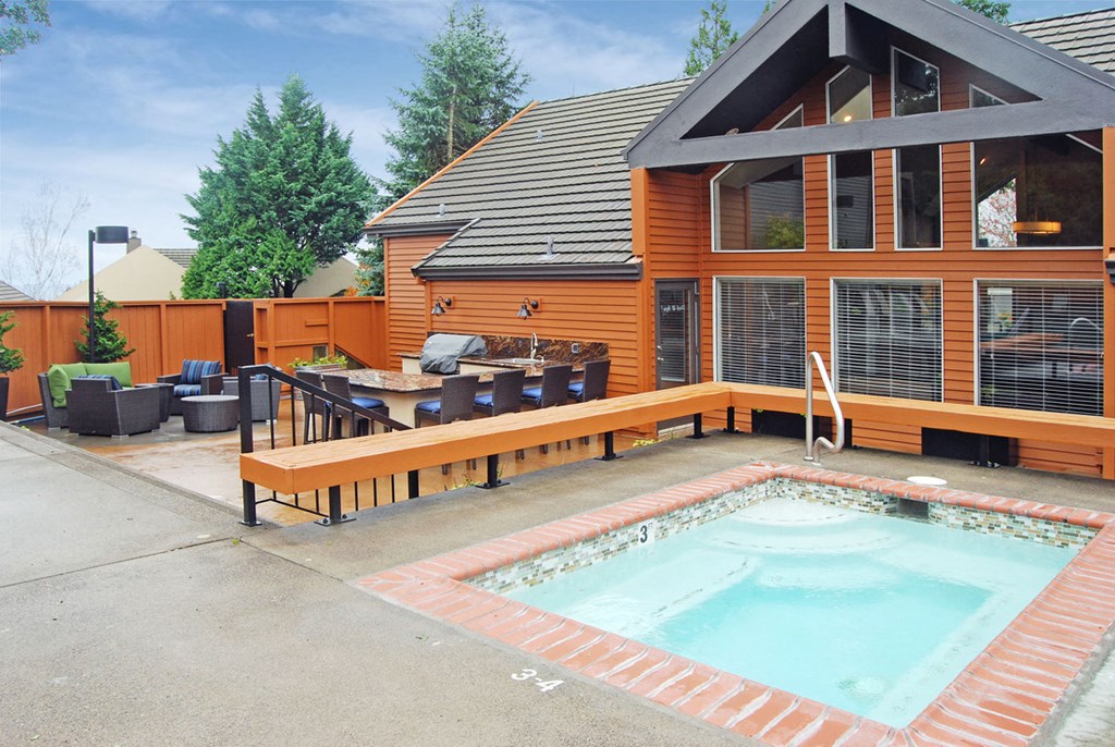 a swimming pool in front of a house with a patio