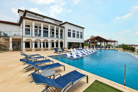 A pool with lounge chairs and a building in the background.