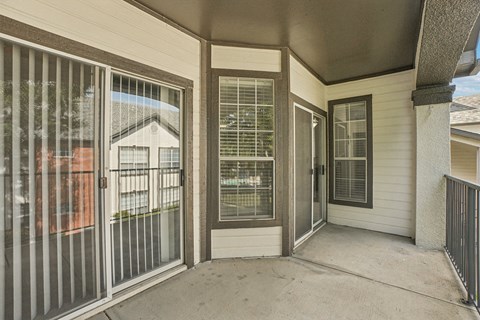 A patio with a sliding glass door and a metal railing.