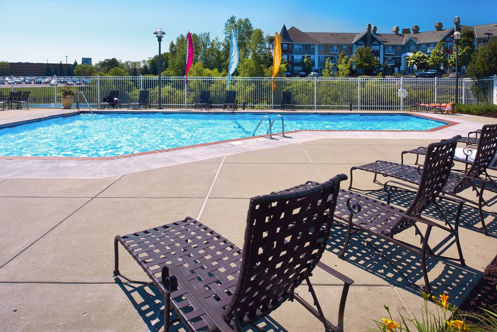 a swimming pool with patio furniture and chairs next to it