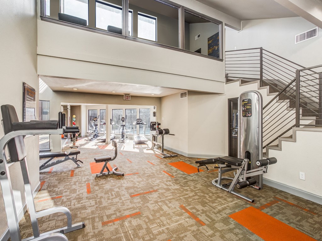a gym with weights and cardio equipment and a spiral staircase