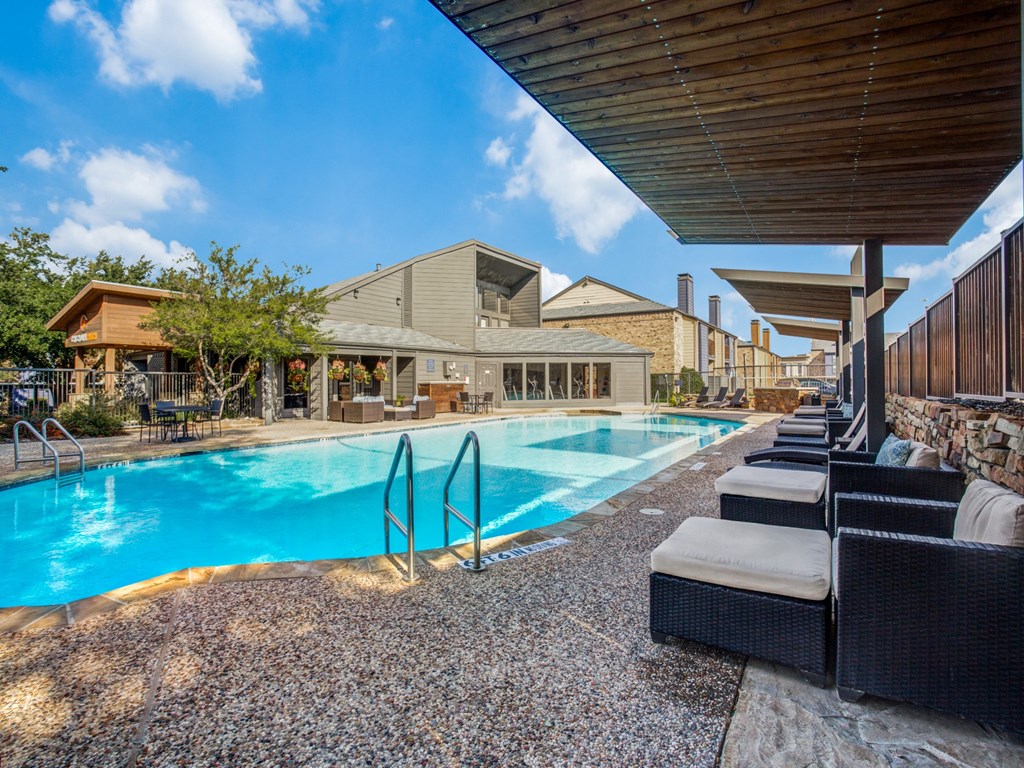 a swimming pool with chairs and a building in the background