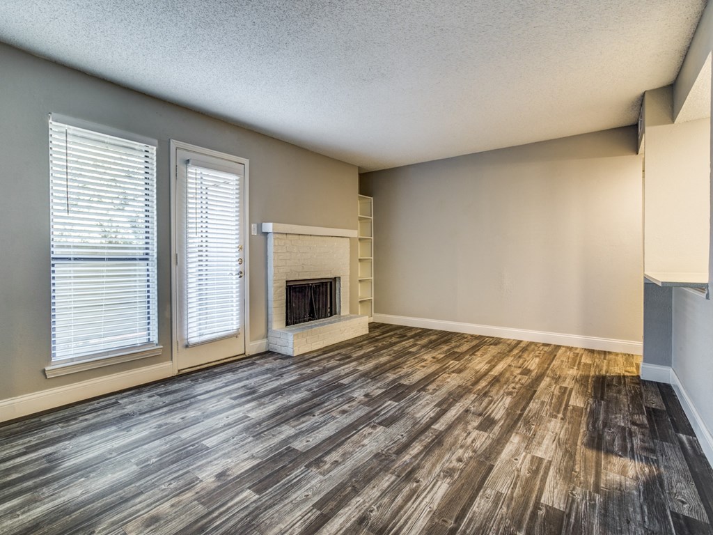 an empty living room with a fireplace and wooden floors