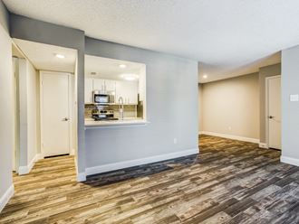 an empty living room with a kitchen in the background