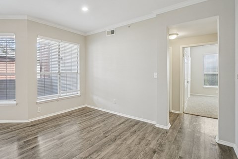 A room with wooden flooring and a window with blinds.