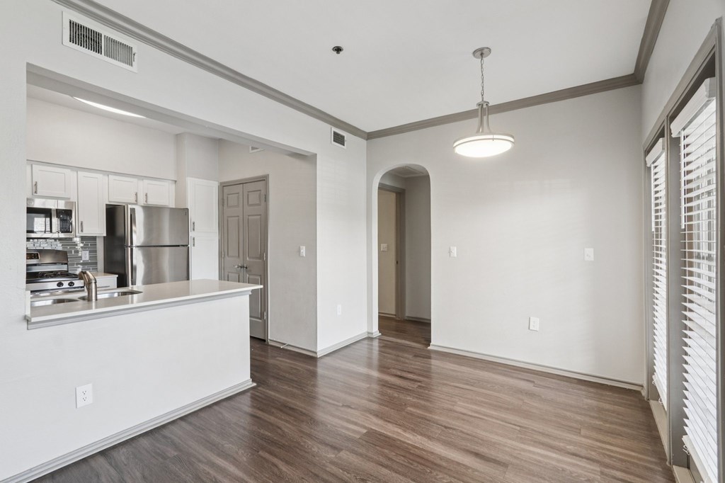 A kitchen with white cabinets and a wooden floor.