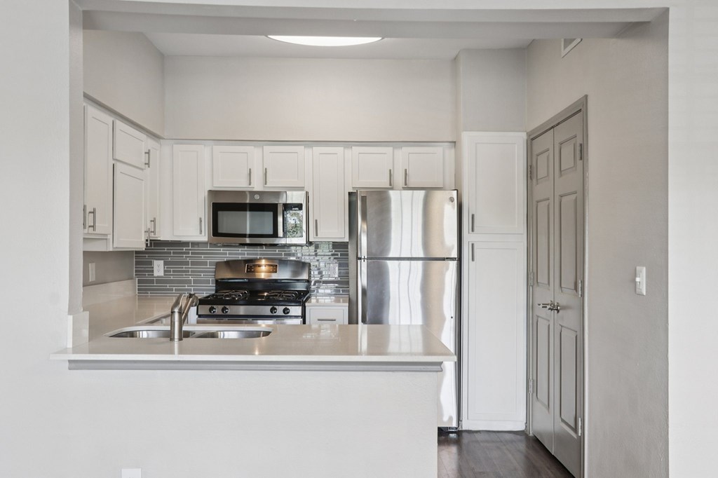 A kitchen with a stove, refrigerator, and microwave.
