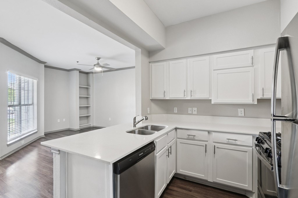 A modern kitchen with white cabinets and stainless steel appliances.