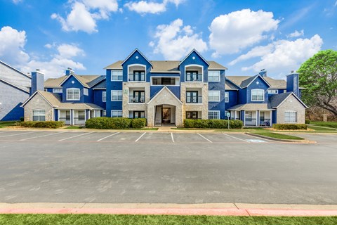 A large blue building with a parking lot in front.